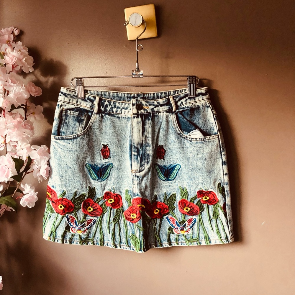 Stonewashed bottom mini denim skirt with embroidered designs.